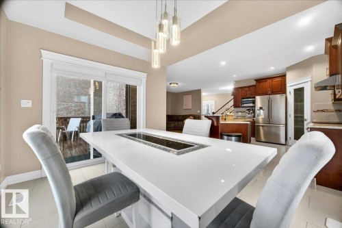 Spacious dining area featuring a large central island with a built-in trough, overhead pendant lighting, and tiled flooring - 1326 Cunningham Drive, Edmonton, AB 