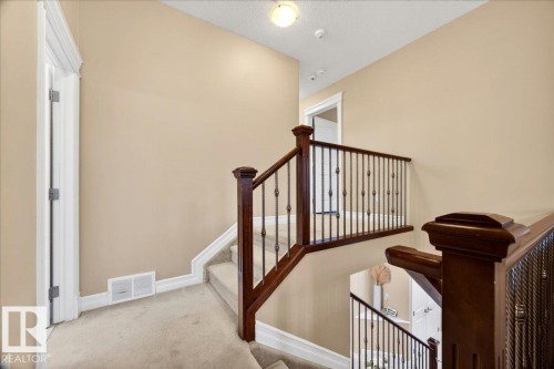 Staircase with wood newel posts and handrails, featuring black metal balusters - 1326 Cunningham Drive, Edmonton, AB 