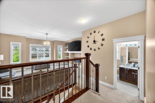 Upper-level landing with carpet flooring and a dark wood and metal baluster staircase - 1326 Cunningham Drive, Edmonton, AB 