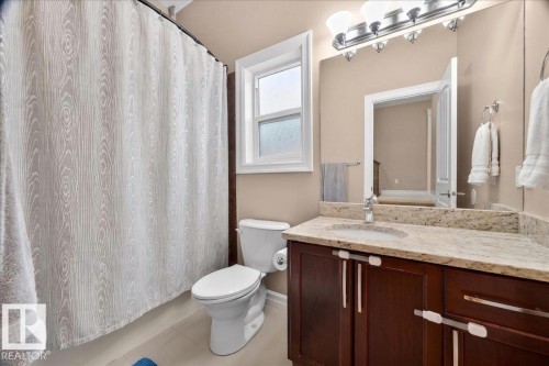 Bathroom vanity featuring a light-toned granite countertop, undermount sink, and dark wood cabinetry - 1326 Cunningham Drive, Edmonton, AB 