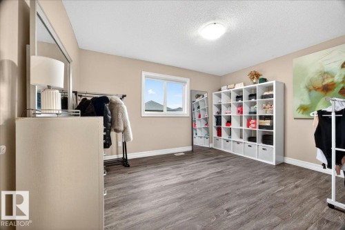 Spacious room featuring wood-finish flooring, a contemporary window, and a built-in modular storage system - 1326 Cunningham Drive, Edmonton, AB 