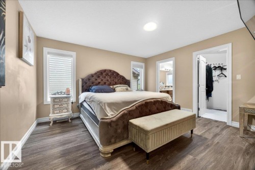 Spacious bedroom featuring wood-finish flooring, two windows with white trim, and a built-in ceiling light fixture - 1326 Cunningham Drive, Edmonton, AB 
