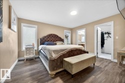 Spacious bedroom featuring wood-finish flooring, two windows with white trim, and a built-in ceiling light fixture - 