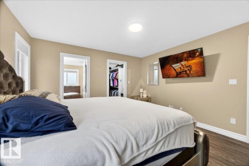 Bedroom featuring wood-finish flooring, neutral wall tones, and white trim - 1326 Cunningham Drive, Edmonton, AB 