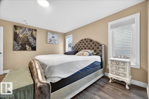 Bedroom featuring wood-finish flooring, neutral wall paint, and a white trim window - 1326 Cunningham Drive, Edmonton, AB 