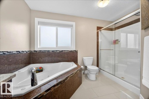 Spacious bathroom featuring a built-in jetted tub with granite surround and mosaic tile accents - 1326 Cunningham Drive, Edmonton, AB 
