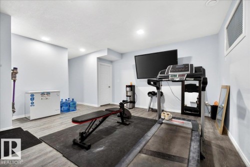 Versatile bonus room featuring wood-finish flooring and light blue walls - 1326 Cunningham Drive, Edmonton, AB 
