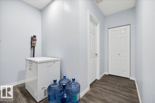 Hallway with wood-finish flooring, light-toned walls, a standard white door, and a white bi-fold closet door - 1326 Cunningham Drive, Edmonton, AB 