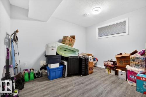 Lower-level room featuring light gray walls, wood-finish flooring, and a single horizontal window with blinds - 1326 Cunningham Drive, Edmonton, AB 
