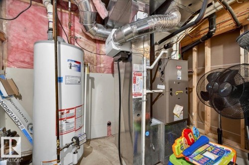 Dedicated utility area featuring a water heater, furnace, exposed ductwork, and plumbing - 1326 Cunningham Drive, Edmonton, AB 
