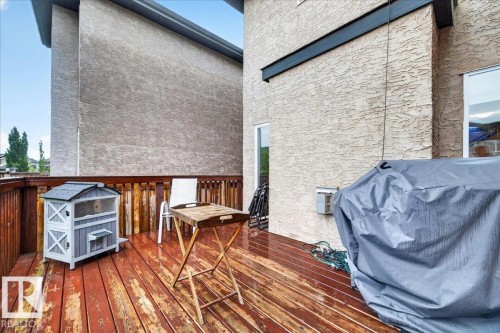 Spacious wood-finish deck with natural wood railing, featuring a neutral stucco exterior and exterior windows - 1326 Cunningham Drive, Edmonton, AB 