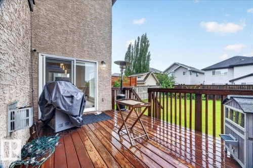 Expansive wood deck with dark stain, featuring a sliding glass door entry to the interior - 1326 Cunningham Drive, Edmonton, AB 