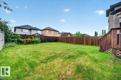 Expansive backyard featuring a manicured lawn, a stained wood privacy fence, and a wooden deck with lattice skirting - 1326 Cunningham Drive, Edmonton, AB 