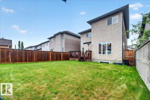 Spacious backyard featuring a wooden privacy fence, a multi-level deck, and a stucco exterior - 1326 Cunningham Drive, Edmonton, AB 