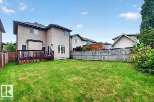 Expansive backyard featuring a wood deck with lattice skirting, a manicured lawn, and perimeter fencing - 1326 Cunningham Drive, Edmonton, AB 