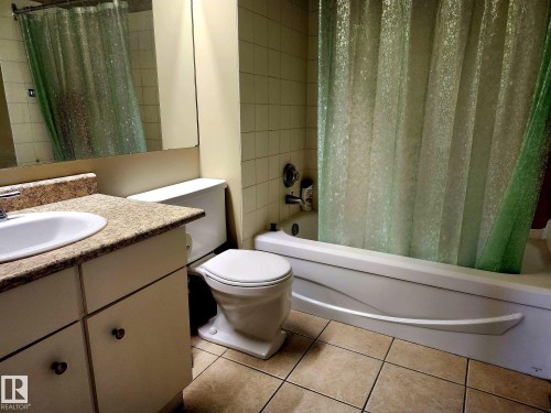 Bathroom featuring a white bathtub, ceramic tile flooring, and a vanity with a white sink and patterned countertop - 1600 10149 Saskatchewan Drive, Edmonton, AB 