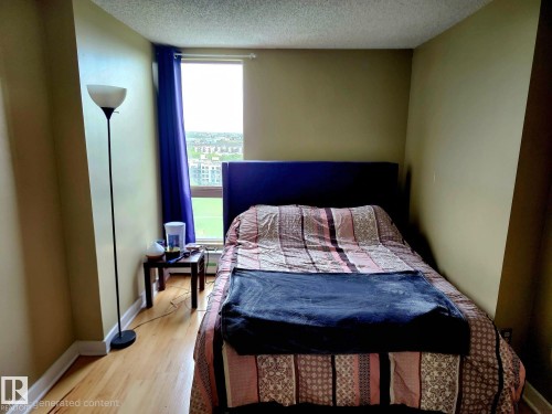 Room featuring wood-finish flooring, a window with a city backdrop, light-toned walls, and white baseboards - 1600 10149 Saskatchewan Drive, Edmonton, AB 