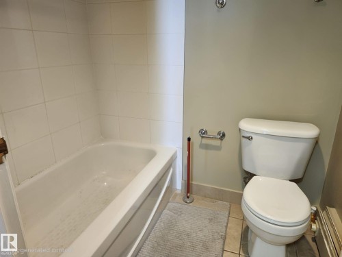 White tiled bathtub and shower surround with a built-in toilet and neutral wall paint - 1600 10149 Saskatchewan Drive, Edmonton, AB 