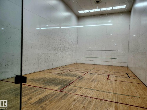 Indoor racquetball court featuring wood-finish flooring, white panel walls, and recessed lighting - 1600 10149 Saskatchewan Drive, Edmonton, AB 