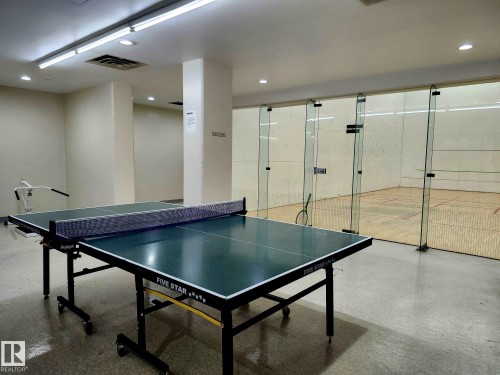 Recreation room featuring a ping-pong table on a polished concrete floor, with a glass-enclosed squash court visible - 1600 10149 Saskatchewan Drive, Edmonton, AB 