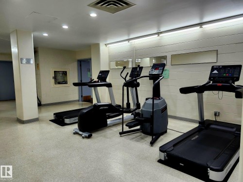 Dedicated fitness room featuring cardio machines, recessed lighting, and wall-mounted mirrors - 1600 10149 Saskatchewan Drive, Edmonton, AB 
