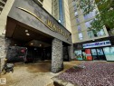 Building entrance featuring a stone-clad facade, covered entryway, and a prominent building sign - 1600 10149 Saskatchewan Drive, Edmonton, AB 