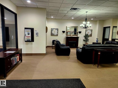 Spacious common area featuring a decorative fireplace, chandelier lighting, and recessed ceiling lights - 1600 10149 Saskatchewan Drive, Edmonton, AB 