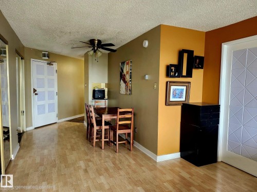 Open-concept living area featuring wood-finish flooring, a ceiling fan, and a paneled entry door - 1600 10149 Saskatchewan Drive, Edmonton, AB 