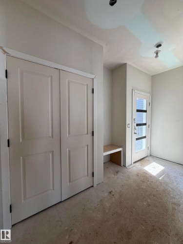 Entryway featuring double panel doors, built-in bench seating, and a glass-paneled entry door - 2206 Crossbill Link, Edmonton, AB 