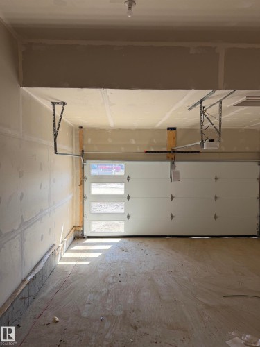 Spacious garage with a modern white overhead door featuring four horizontal window panels - 2206 Crossbill Link, Edmonton, AB 