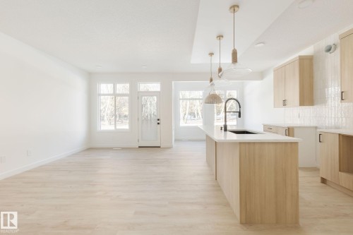 Bright, open-concept room featuring light-toned walls and herringbone-patterned wood-finish flooring - 2206 Crossbill Link, Edmonton, AB 