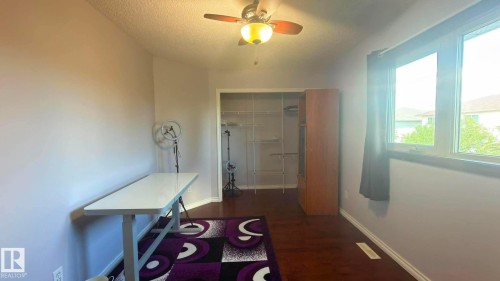 Bright room featuring hardwood flooring, a ceiling fan with integrated lighting, and a large window with dark trim. - 825 112B St, Edmonton, AB 