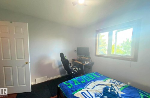 Light-filled room featuring a large window with wood trim, light wall color, white paneled door, and a ceiling fan. - 825 112B St, Edmonton, AB 