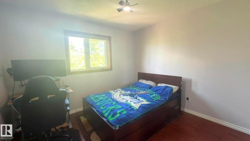Room featuring a window with wood trim, a ceiling fan with integrated lighting, Hardwood flooring, and light-toned walls. - 825 112B St, Edmonton, AB 