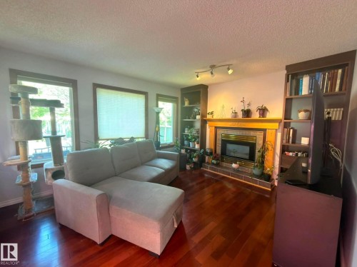 Living area featuring a central gas fireplace with a tile surround and wood mantel, flanked by built-in bookshelves. - 825 112B St, Edmonton, AB 