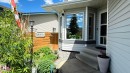 Exterior featuring light grey siding, a multi-pane bay window, and a white storm door. Two trees in the front garden will be removed. - 825 112B St, Edmonton, AB 