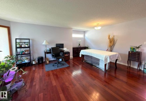 Spacious room featuring rich hardwood flooring, light-toned walls, and a large bay window with wood trim - 825 112B St, Edmonton, AB 