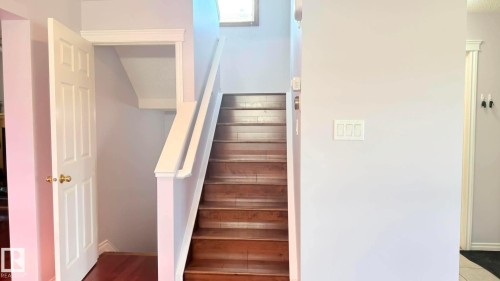 Hardwood staircase featuring white risers and a white banister Leading upstairs and downstairs. - 825 112B St, Edmonton, AB 