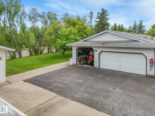 Attached two-car garage with white paneled door, asphalt driveway, and concrete walkways - 11921 231 Street, Edmonton, AB 