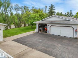 Attached two-car garage with white paneled door, asphalt driveway, and concrete walkways - 
