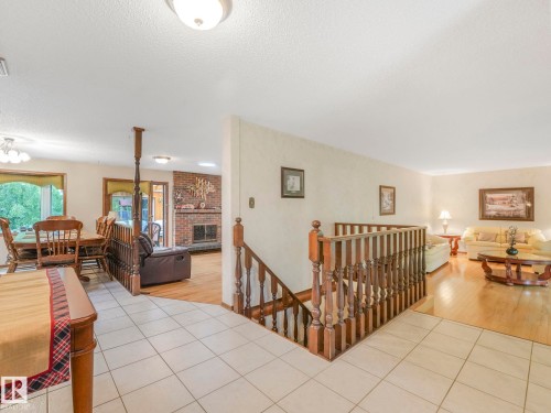Split-level interior featuring tile flooring at the entry, wood-finish flooring in living areas, a brick-faced fireplace, and wooden stair railings - 11921 231 Street, Edmonton, AB 