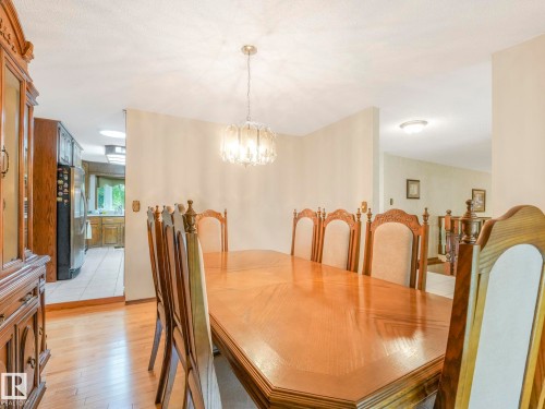 Dining area featuring wood-finish flooring, a contemporary chandelier, and light-toned walls - 11921 231 Street, Edmonton, AB 