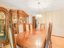 Spacious dining area featuring blonde wood-finish flooring and a central chandelier - 