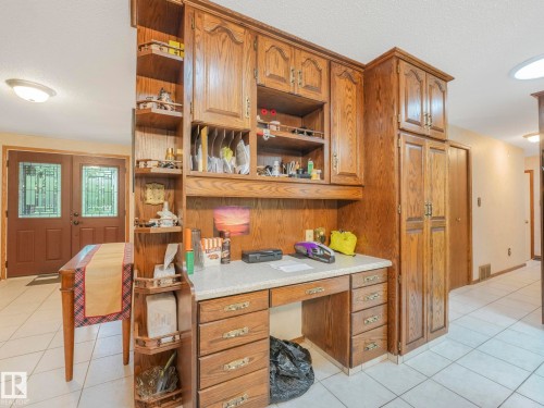 Built-in wooden cabinetry featuring a desk area with a light-toned countertop, multiple storage drawers, and open shelving - 11921 231 Street, Edmonton, AB 