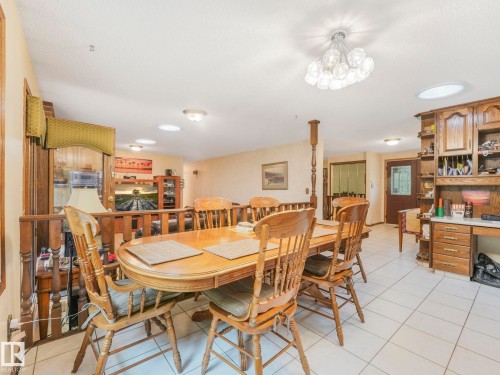 Open-concept dining area featuring light-toned tile flooring, a decorative ceiling fixture, multiple recessed lights, and a built-in wooden hutch with shelving - 11921 231 Street, Edmonton, AB 