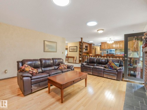 Bright living space featuring light wood-finish flooring, recessed lighting, and a brick fireplace with a stone hearth - 11921 231 Street, Edmonton, AB 