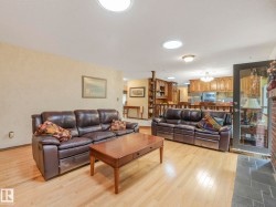 Bright living space featuring light wood-finish flooring, recessed lighting, and a brick fireplace with a stone hearth - 