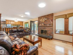 Living area featuring a brick fireplace with a slate hearth, light wood-finish flooring, and multiple windows with valances - 