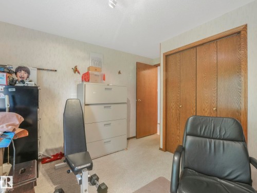 Recessed lighting illuminates a neutral palette room with textured wall finishes, soft carpeting, and a wood-tone bi-fold closet - 11921 231 Street, Edmonton, AB 