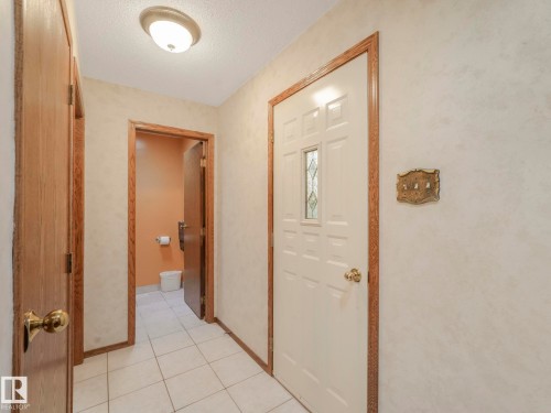Entryway featuring a paneled door with decorative glass inserts, white ceramic tile flooring, and wood-finish trim - 11921 231 Street, Edmonton, AB 